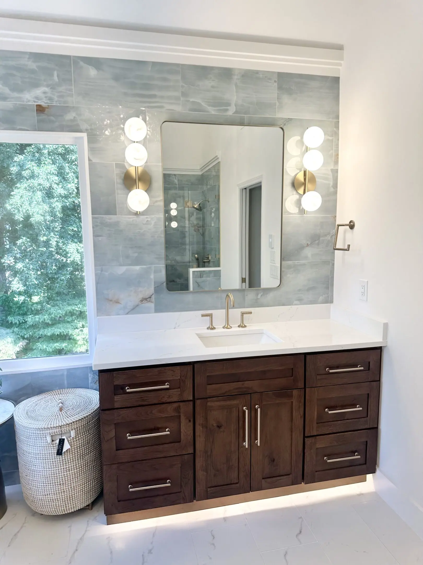 Modern bathroom vanity with dark wood cabinets and marble countertop.