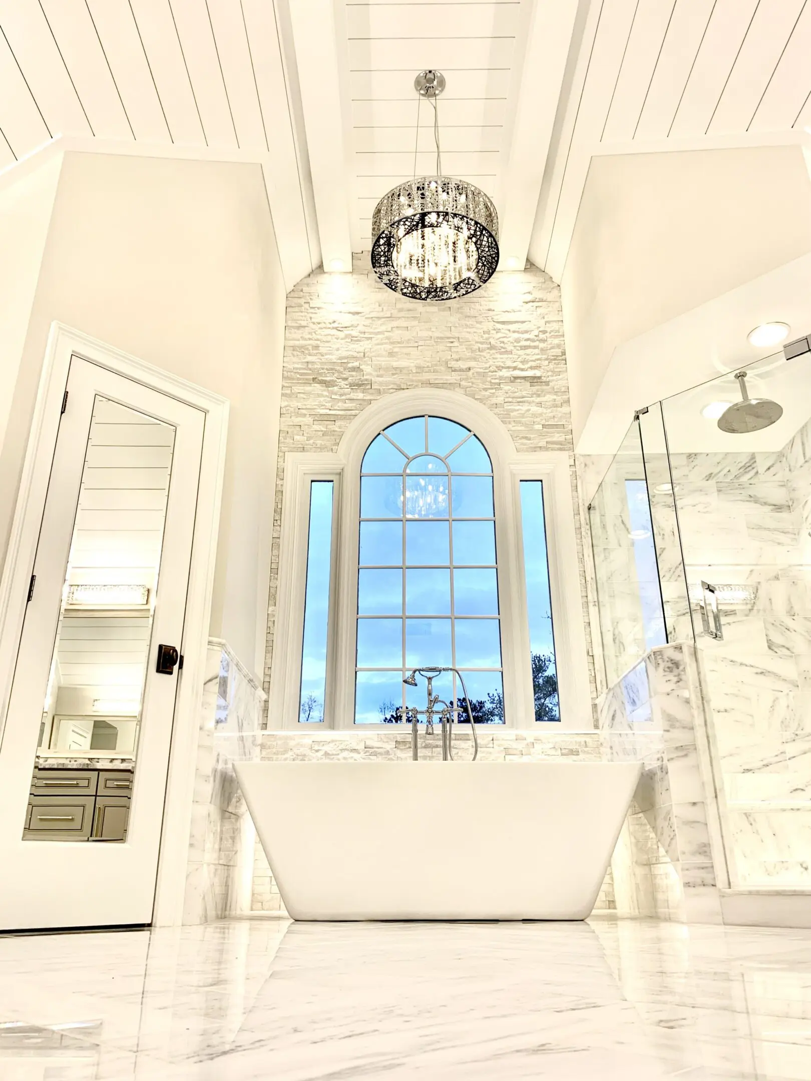 Bright, elegant bathroom with a freestanding tub and large window.