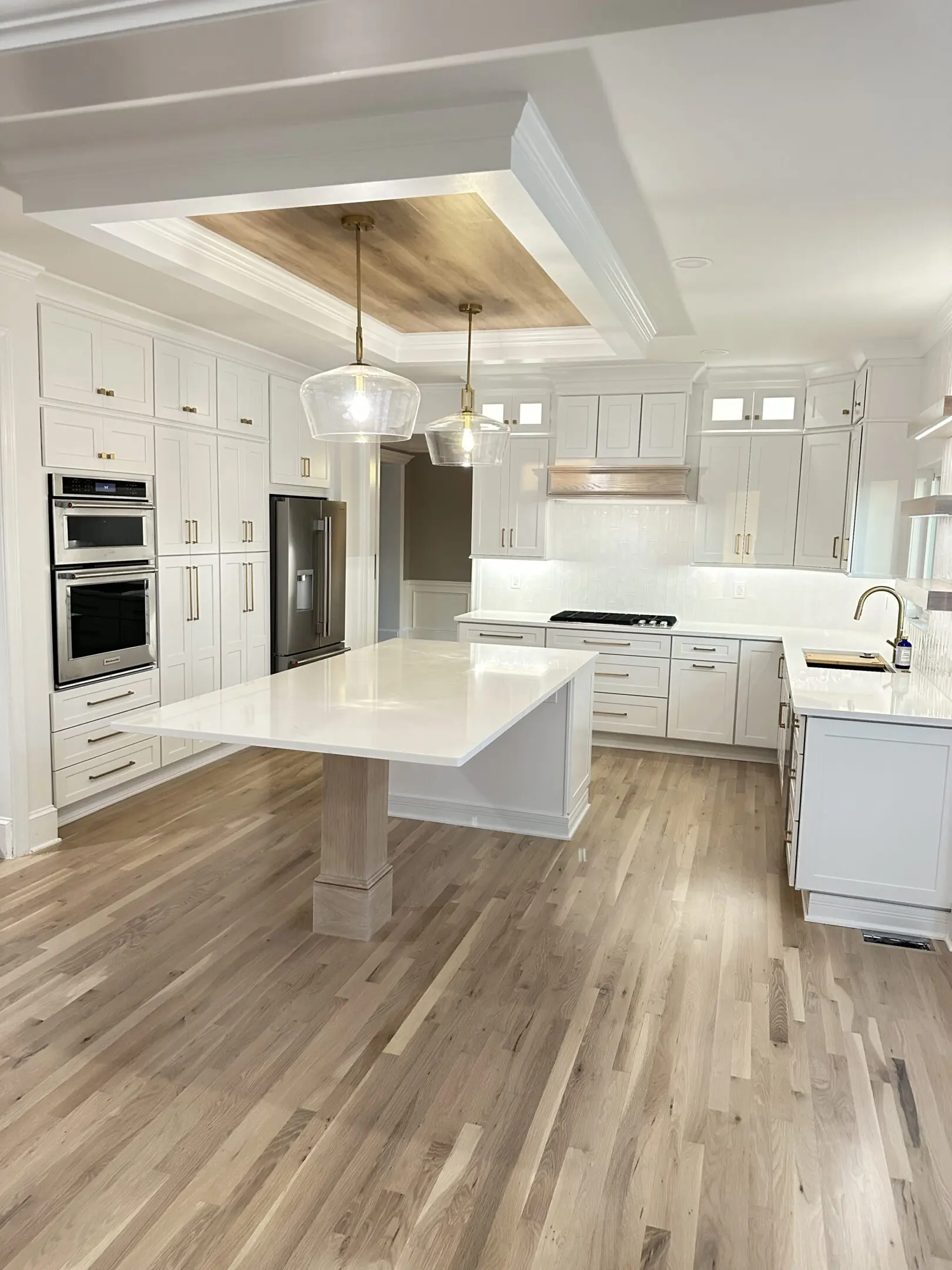 Modern white kitchen with large island and stainless steel appliances.
