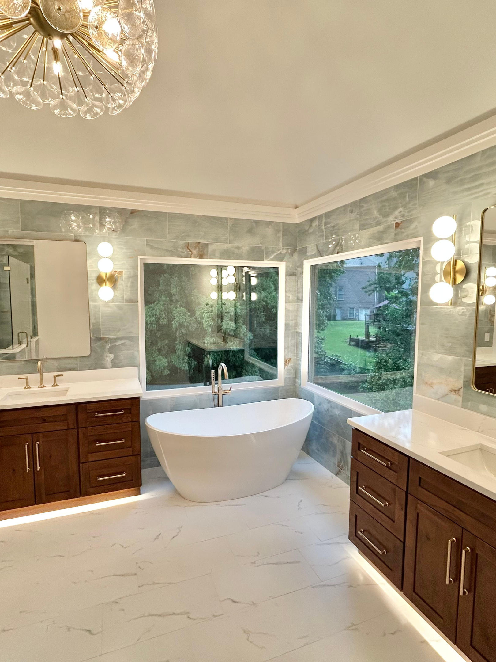 Elegant bathroom with freestanding tub and large windows overlooking greenery.